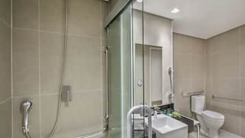 A modern bathroom with a glass-enclosed shower, a white sink, and a toilet.