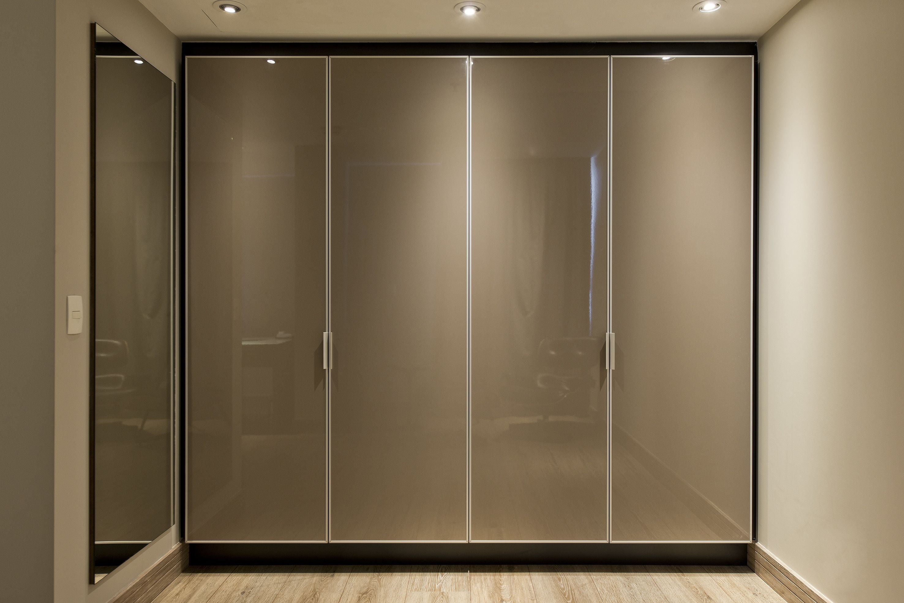 Quarto com grande porta de vidro deslizante, piso de madeira e iluminação embutida no teto.