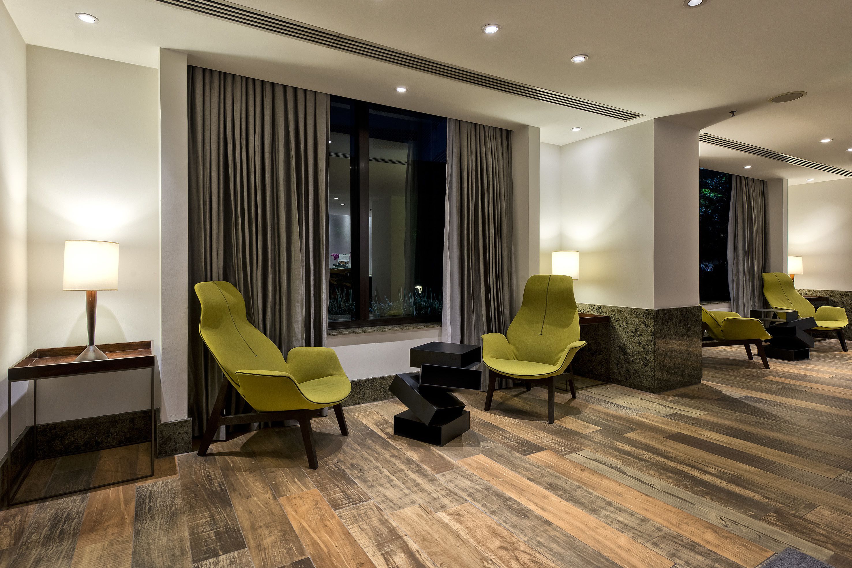 Un hall de hotel con muebles modernos, incluyendo sillas amarillas y una pared de acento de mármol.