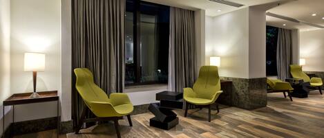 Un hall de hotel con muebles modernos, incluyendo sillas amarillas y una pared de acento de mármol.