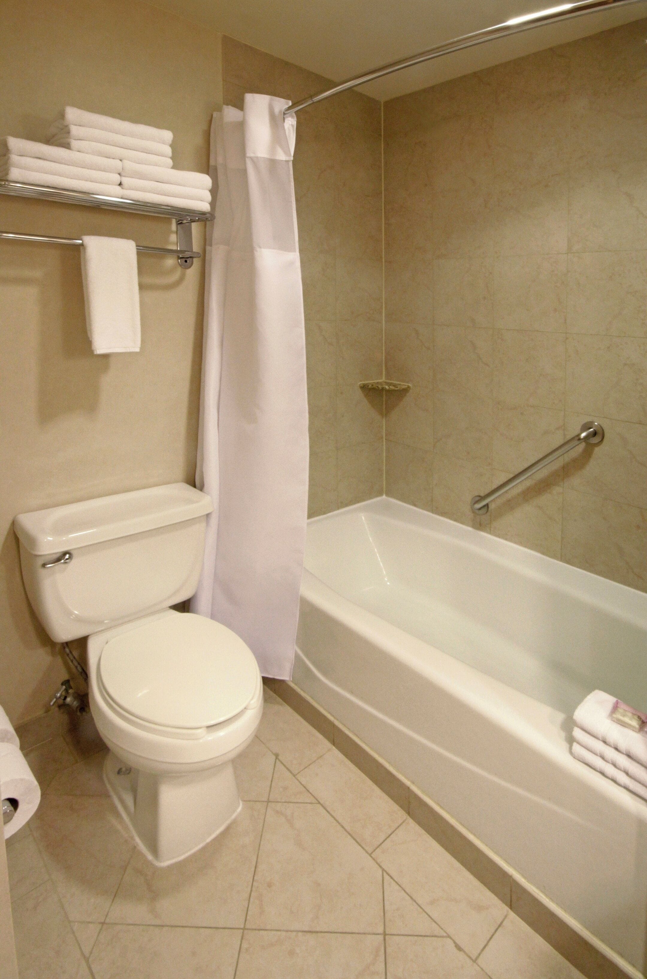 Un baño con inodoro, bañera y cortina de ducha.