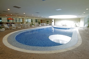 Una piscina interior con sillones de descanso y plantas en macetas.