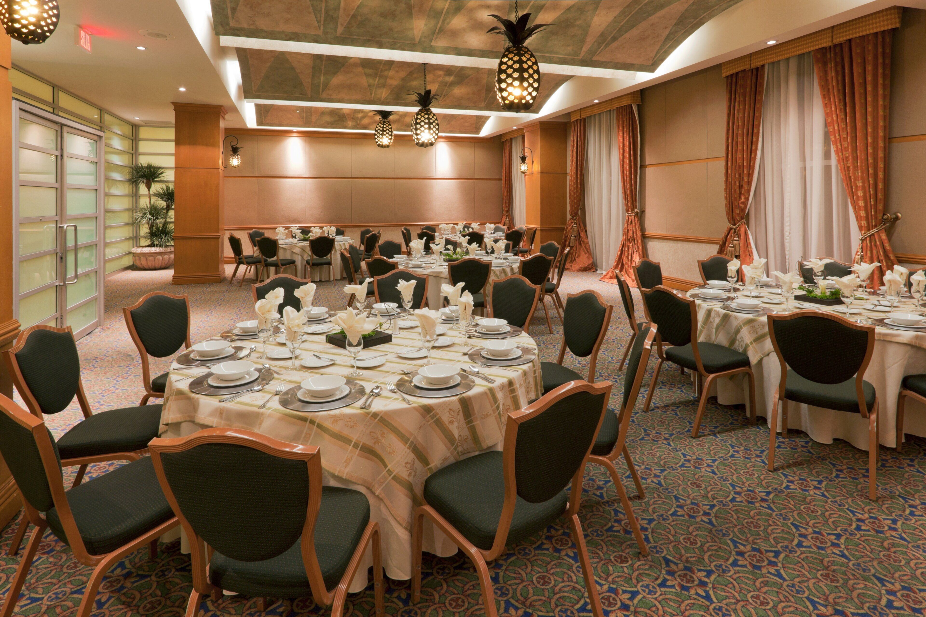 Un salón de conferencias con mesas redondas, sillas y una alfombra estampada.