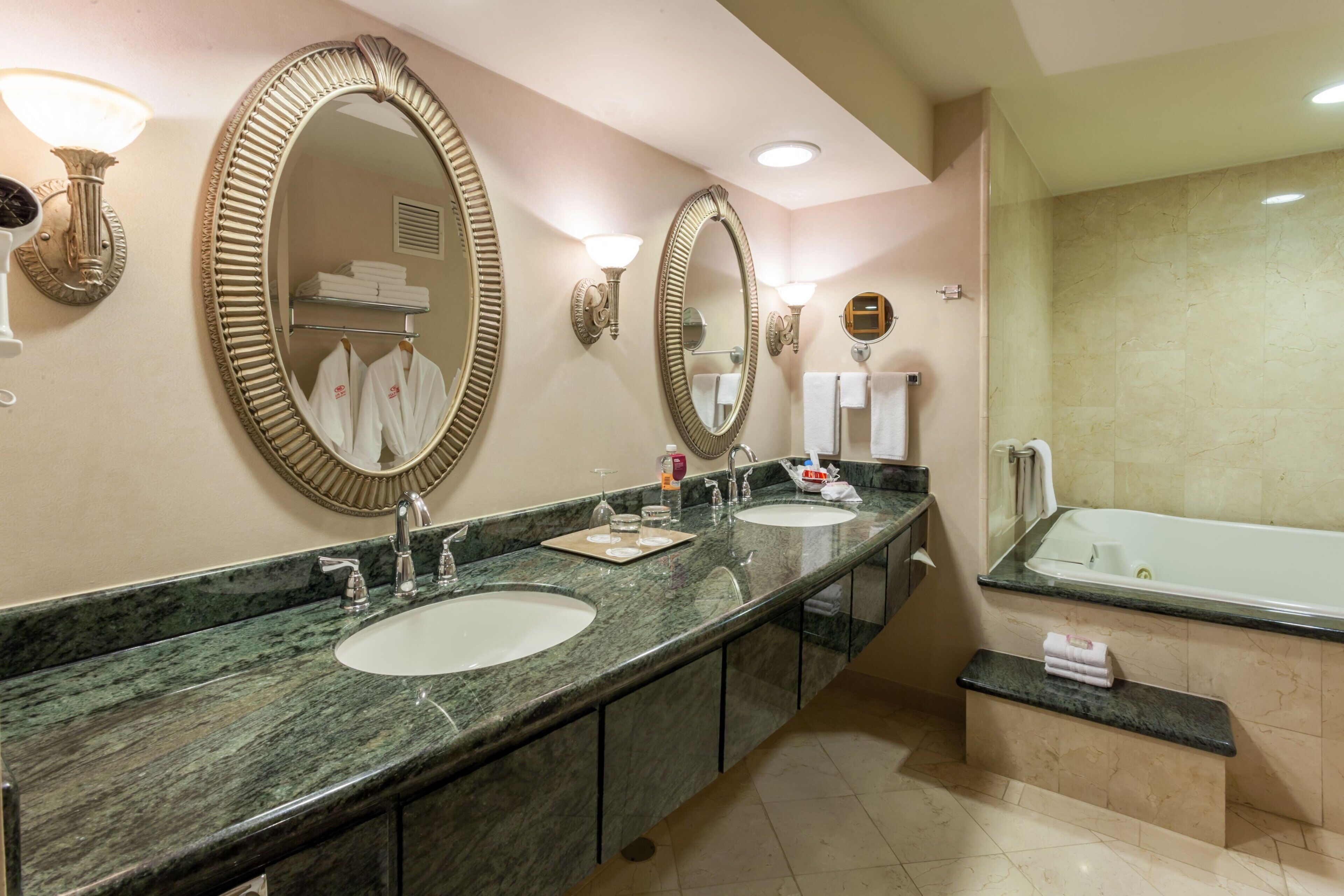Une salle de bain d’hôtel avec deux lavabos, une baignoire et de grands miroirs.