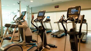 A gym with multiple treadmills and elliptical machines, a digital display showing workout metrics, and a mirror reflecting the equipment. - Crowne Plaza Torreon by IHG (Torreón)
