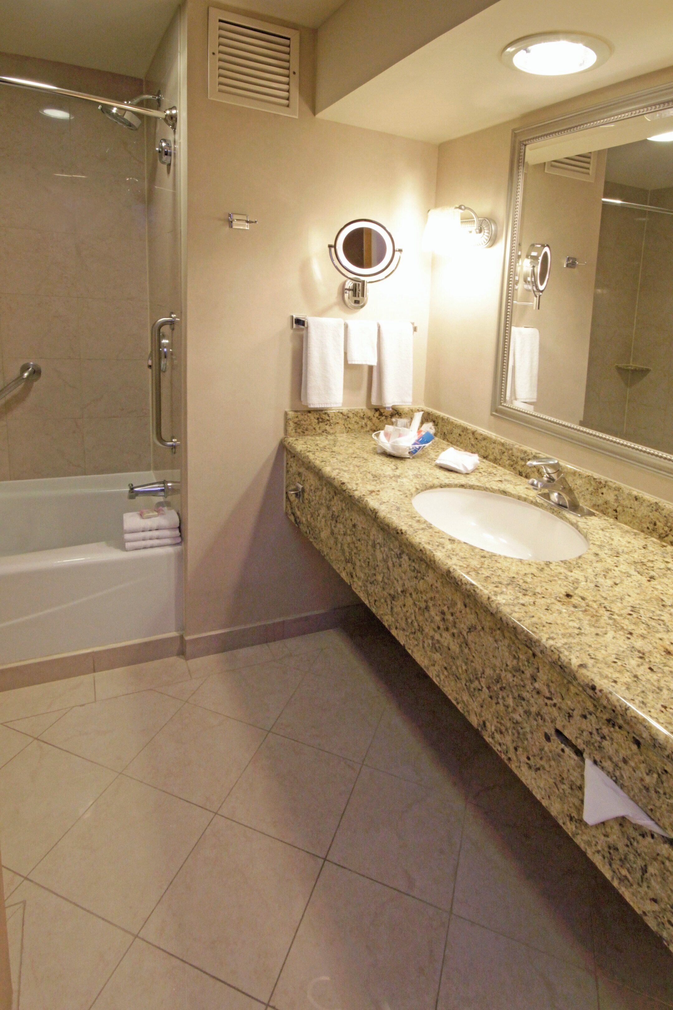 A bathroom with a bathtub, a sink, a mirror, and a shower.