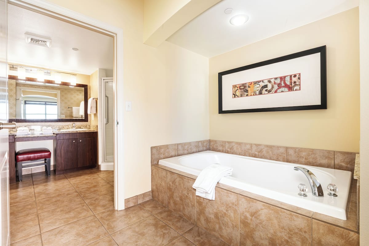 A bathroom with a large bathtub, a sink, and a vanity with a mirror.