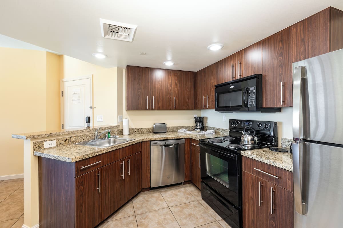 A modern kitchen with granite countertops, stainless steel appliances, and wooden cabinets.