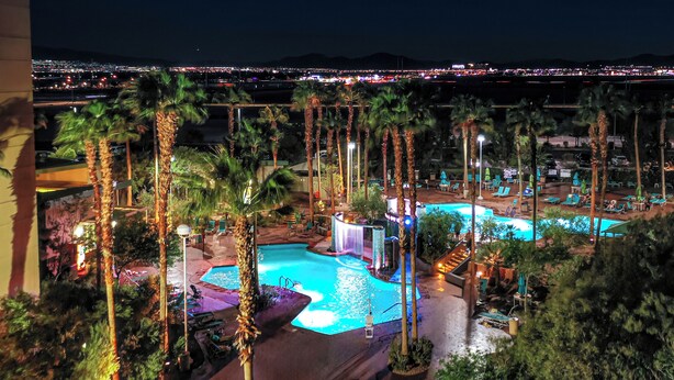 A resort pool area with palm trees, lounge chairs, and a waterfall feature. - Grandview at Las Vegas (Las Vegas)