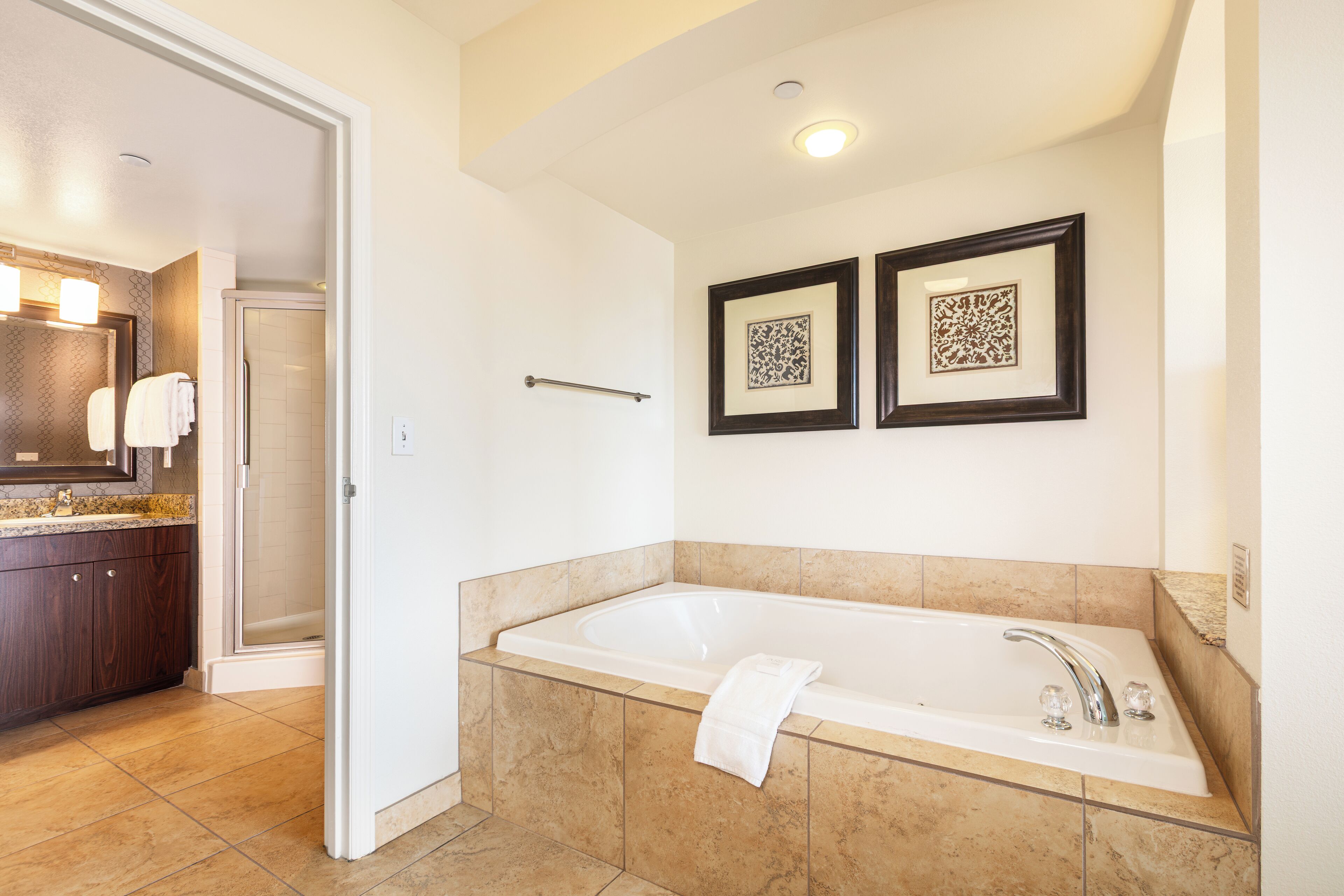 Un bagno moderno con una vasca da bagno ampia, una doccia a filo pavimento e un mobile lavabo con specchio.