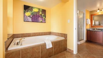 A bathroom with a large bathtub, a shower, and a sink.
