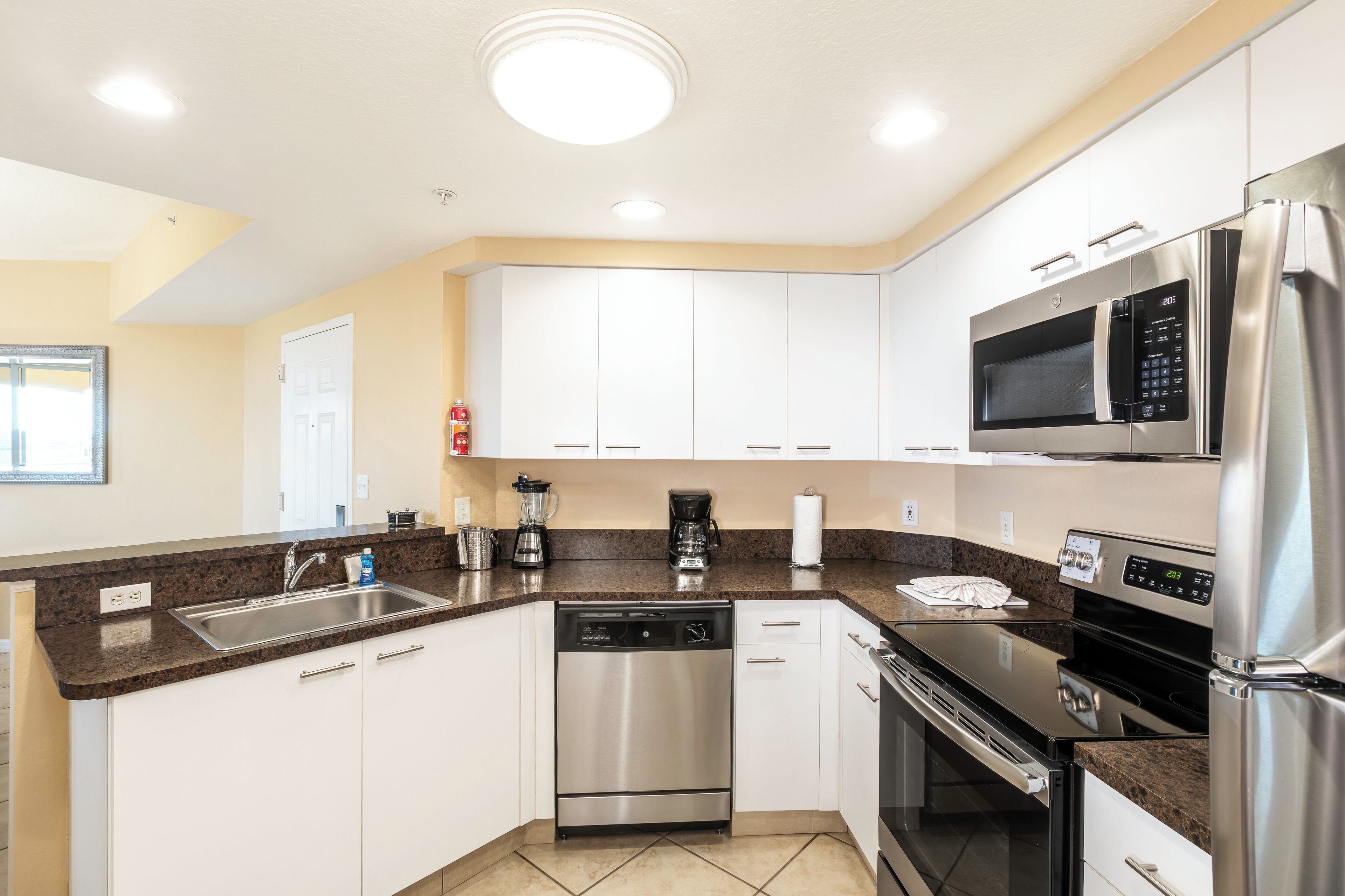 A modern kitchen with stainless steel appliances, white cabinets, and a granite countertop.