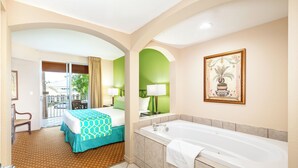 Habitación de hotel con cama, una bañera grande, un sillón y vistas al exterior.