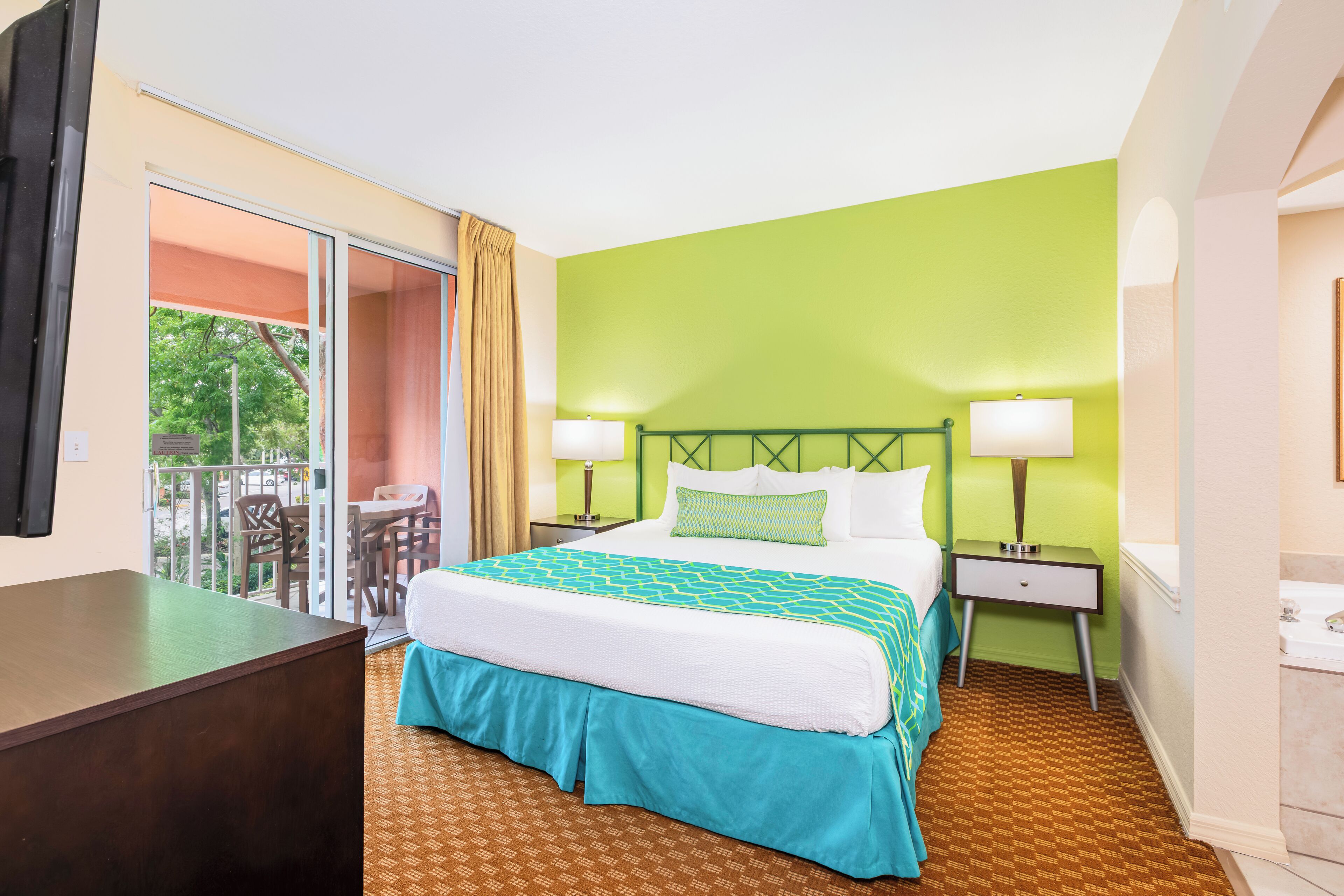 A hotel room with a bed, two bedside tables, a desk, and a chair.