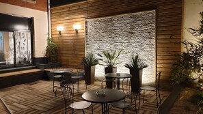 An outdoor patio with wooden flooring, metal tables and chairs, and potted plants. - Hotel Paris Villette (Paris)