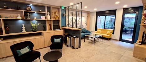 A modern interior with a reception desk, seating area, and a view through a glass door.