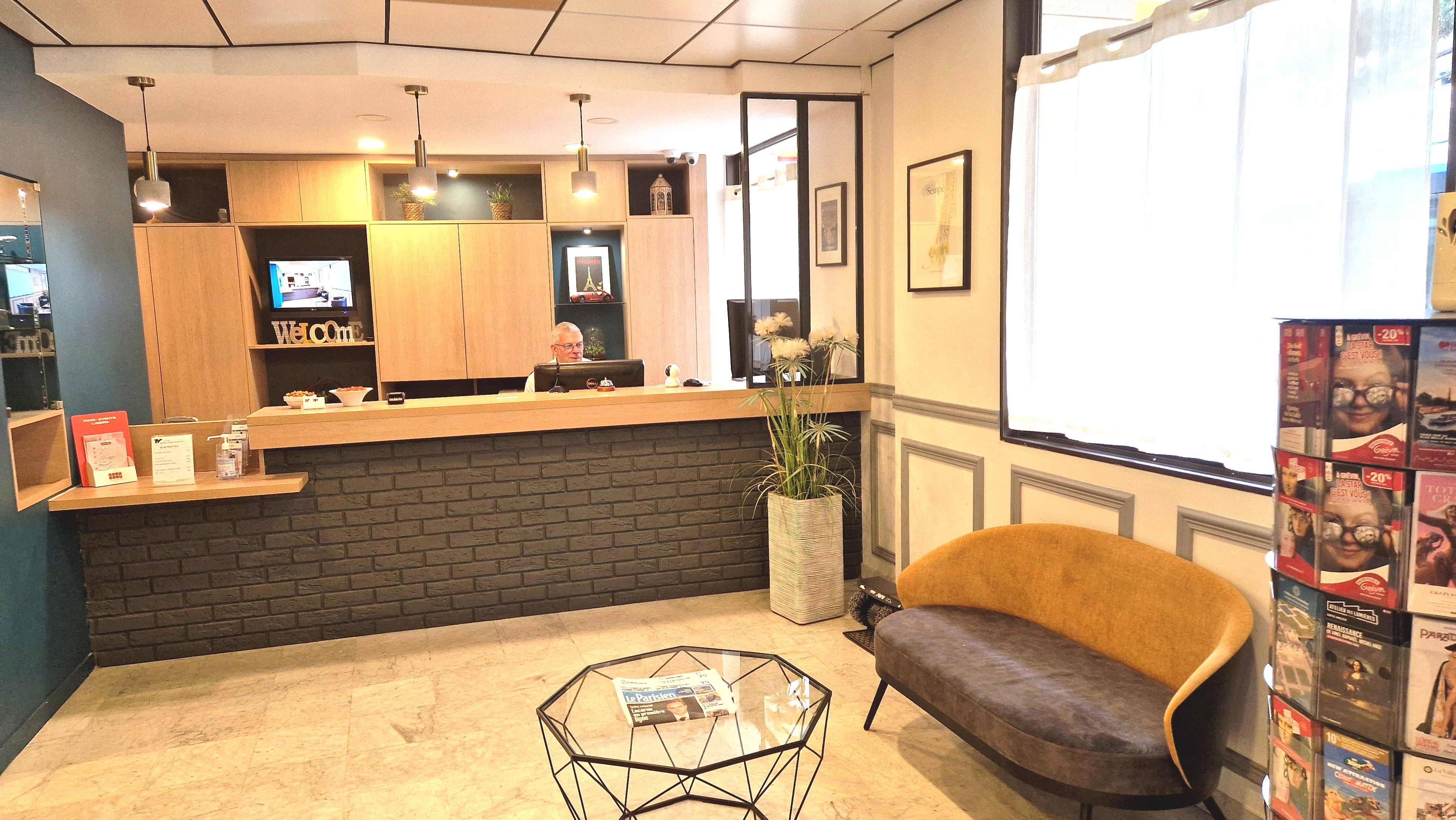 A reception area with a wooden counter, a television, a potted plant, a sofa, and a glass coffee table.