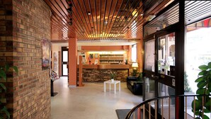 Un hall d’entrée avec un mur en briques, un comptoir d’accueil, une petite table blanche ornée d’une plante et un escalier.