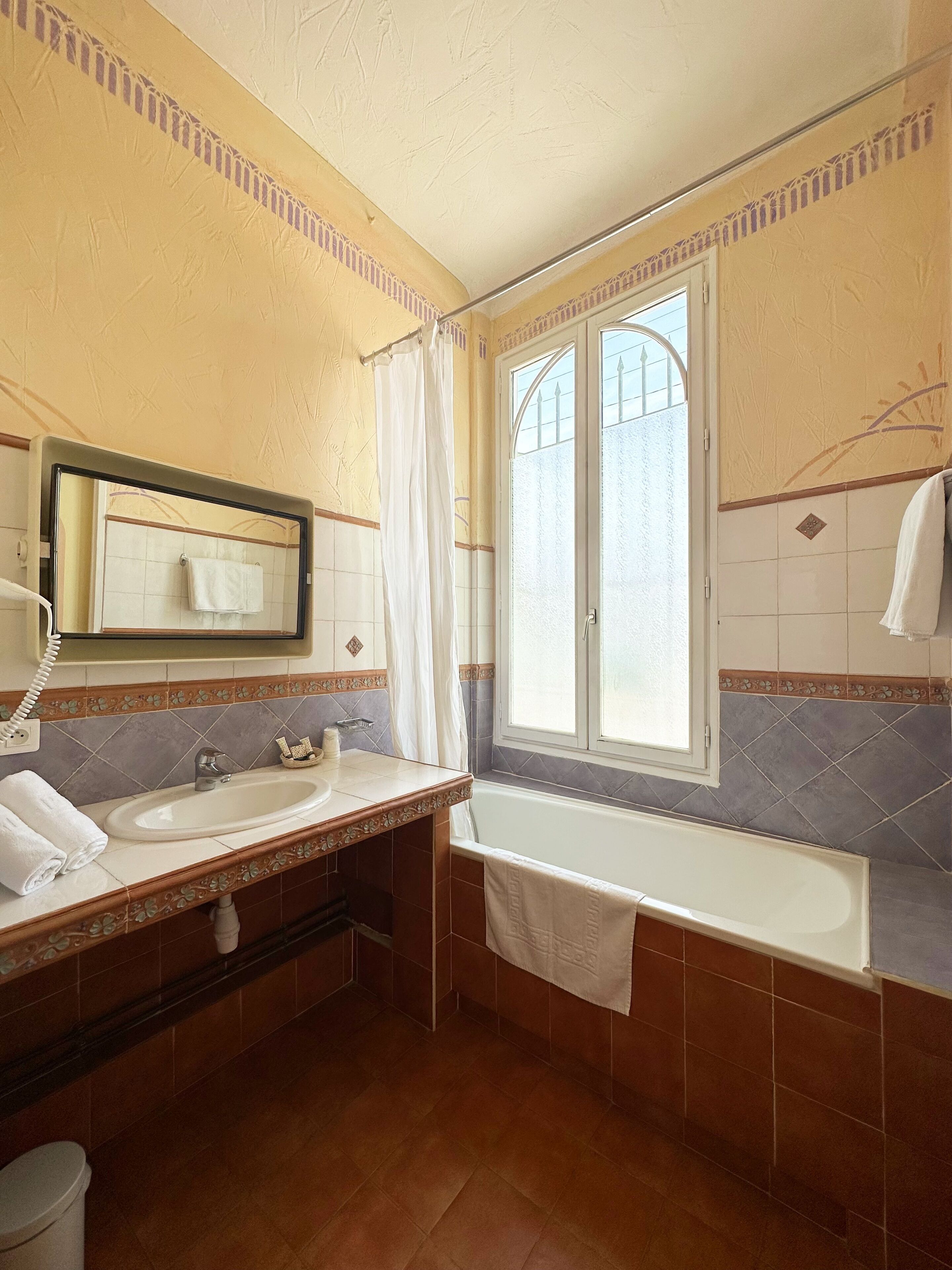 A bathroom with a sink, mirror, and bathtub.