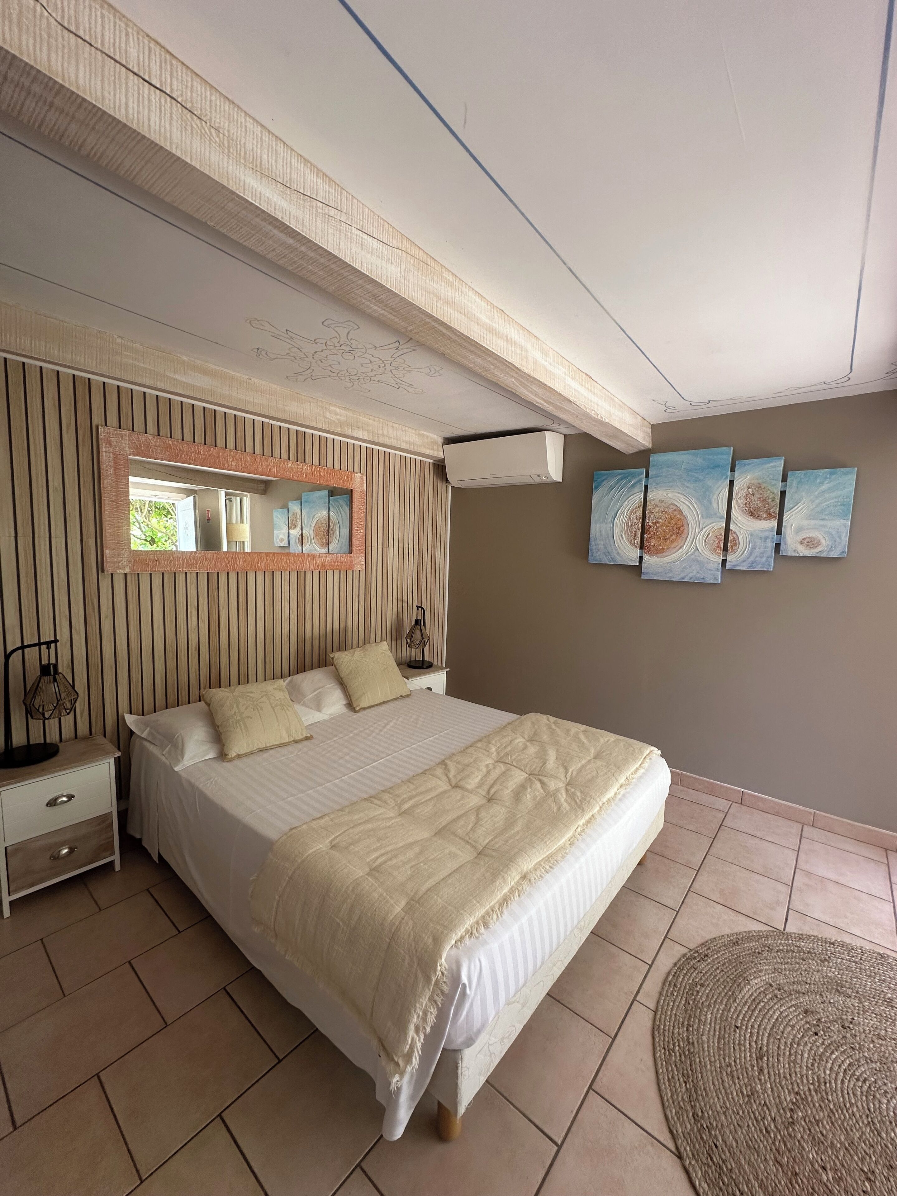 Un dormitorio con una cama grande, una mesita de noche, un espejo y decoración en la pared.