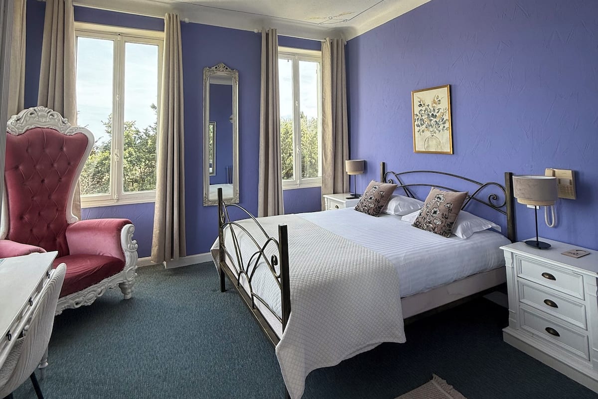 A bedroom with a bed, a chair, a desk, and a dresser.