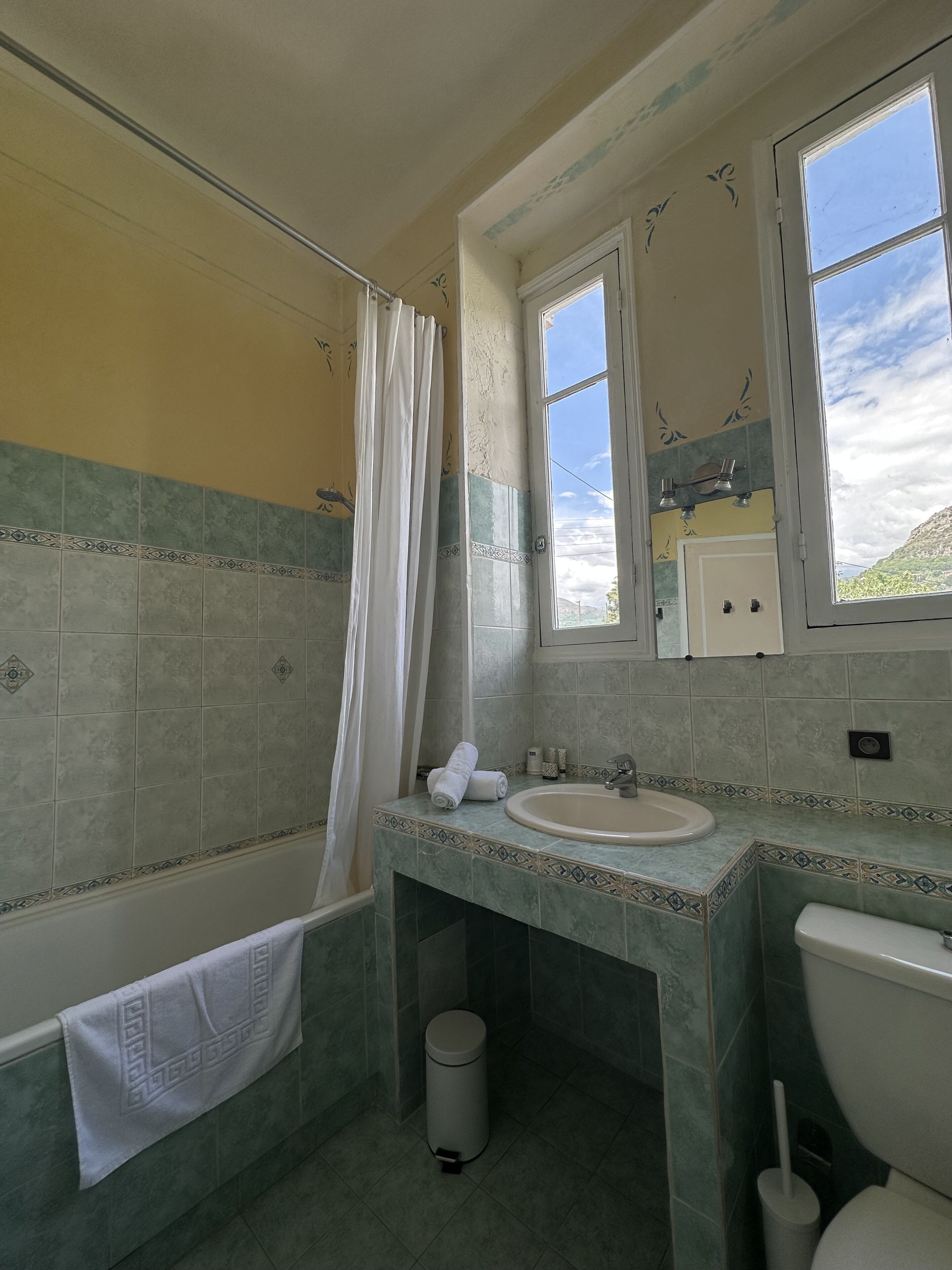 A bathroom with a bathtub, a sink, a toilet, and a window.