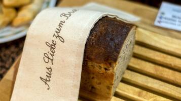 A loaf of bread with a cloth label that reads "Aus Liebe zum Brot" on a wooden surface.