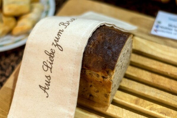 A loaf of bread with a cloth label that reads "Aus Liebe zum Brot" on a wooden surface.