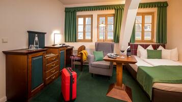 Una habitación de hotel con escritorio, silla, cama y una maleta roja.
