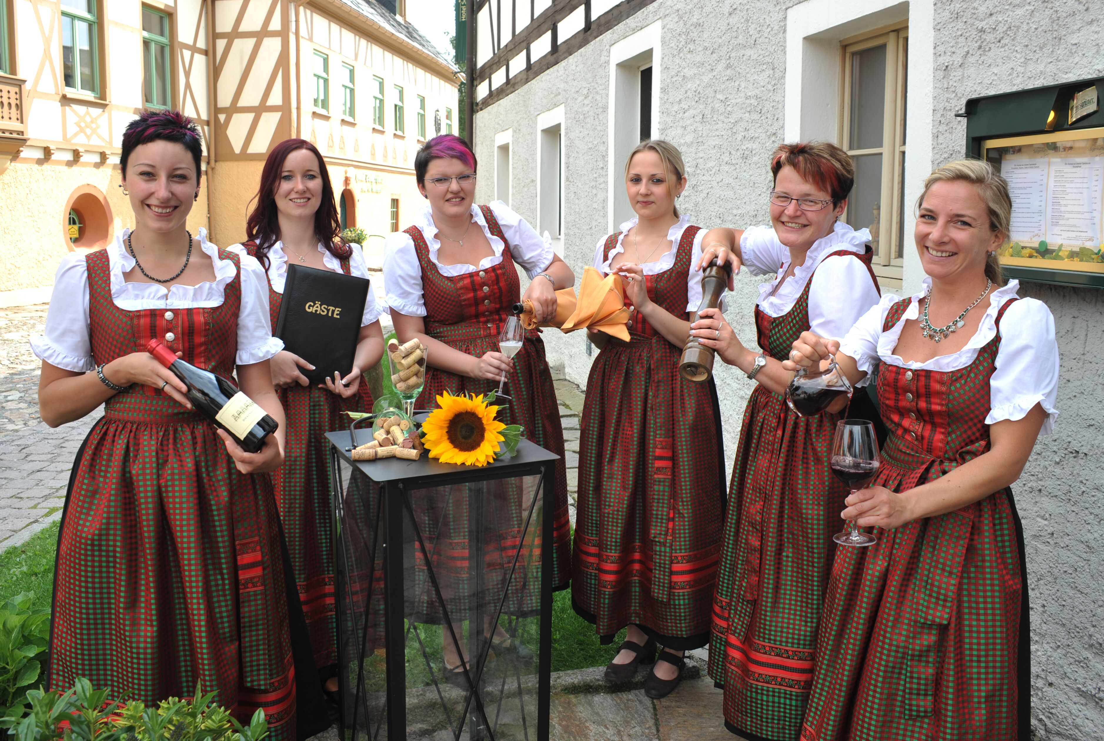 A group of people in traditional attire standing outside a building with a table between them.