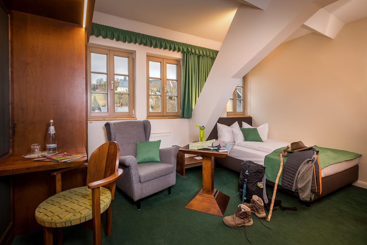 A compact hotel room with a bed, a desk, a chair, and a window with curtains.