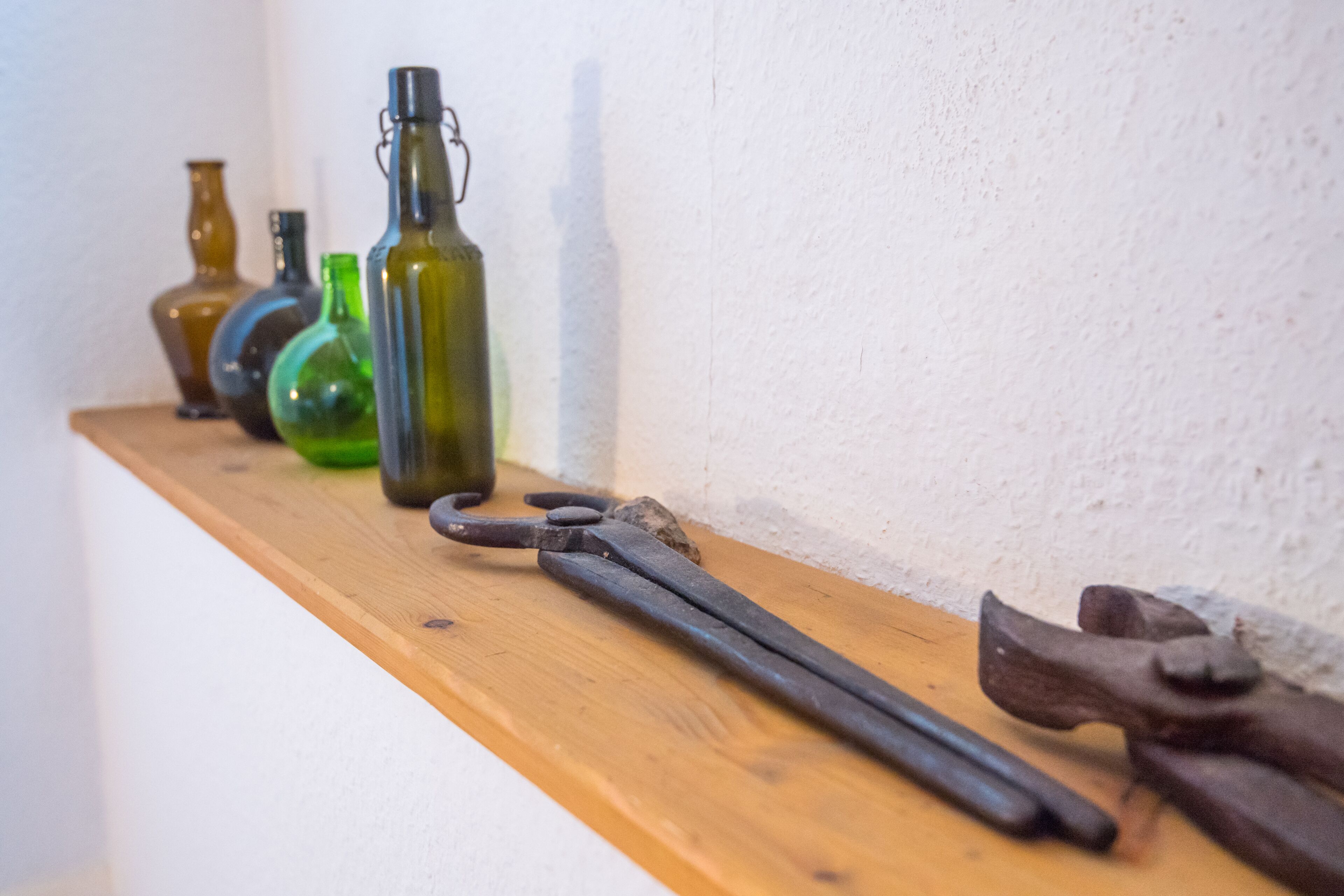 A wooden shelf with various glass bottles and a pair of old-fashioned scissors.