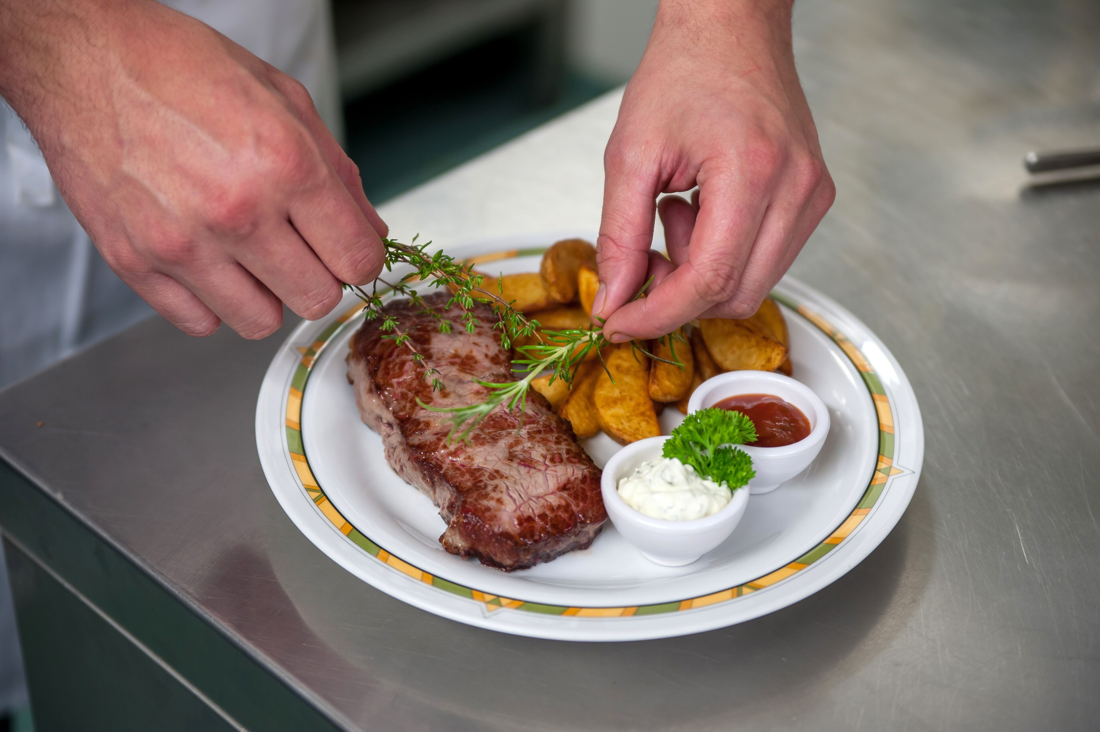 En tallerken med steak, pommes frites og to dressinger.
