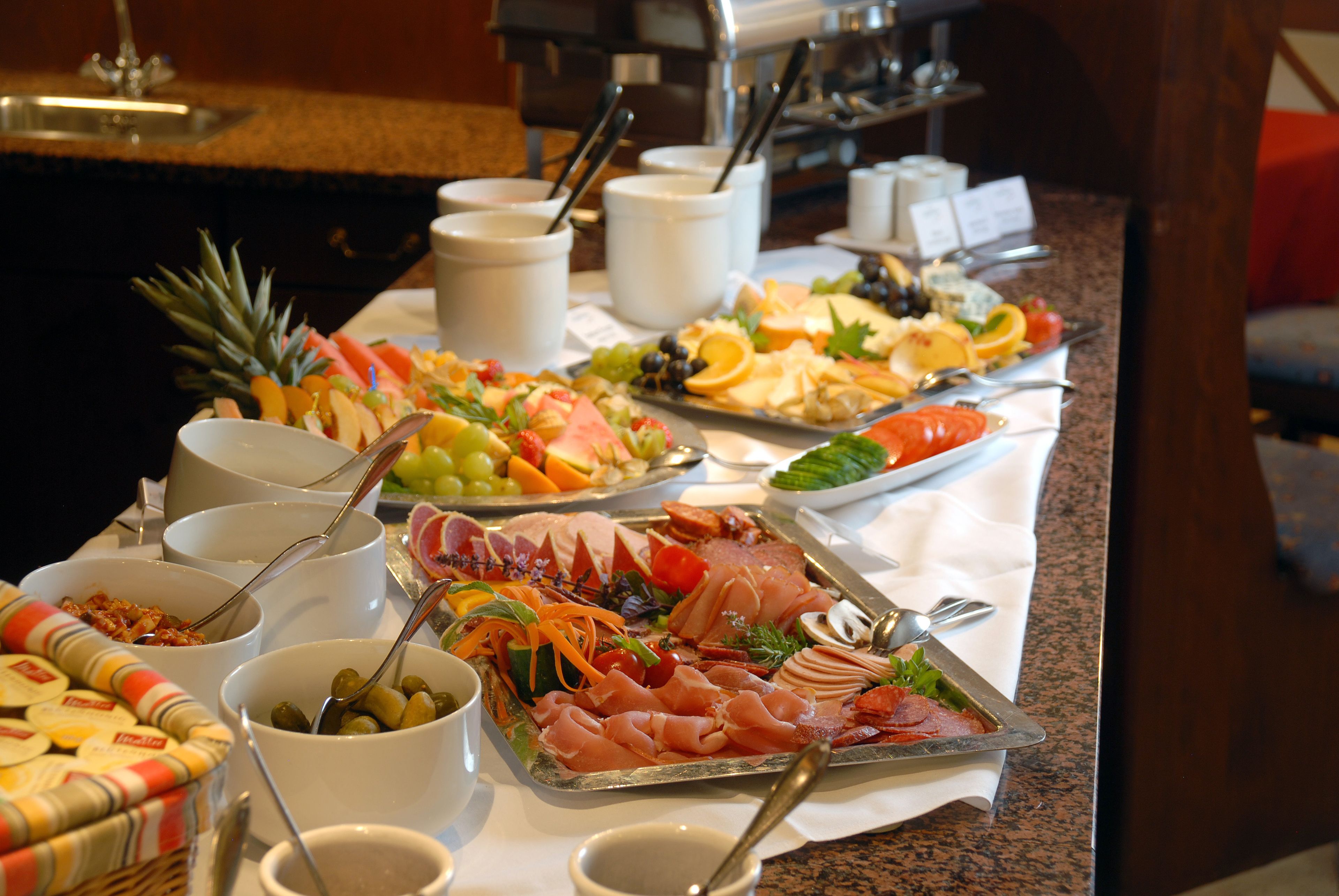 A buffet with various food items including fruits, vegetables, and meats.