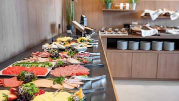 Un bufé con diversas opciones de comida, incluyendo carnes, quesos y verduras.