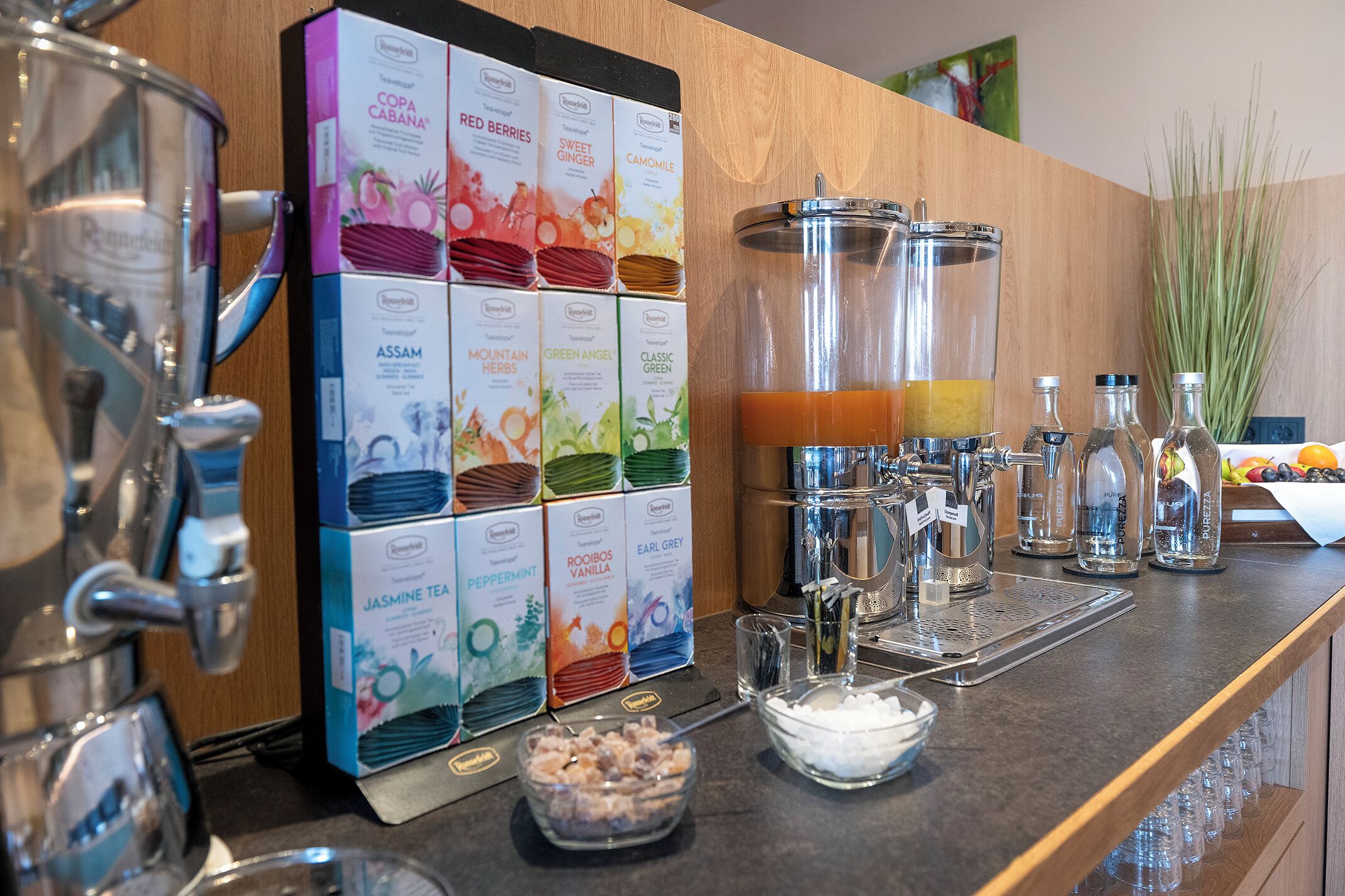 Eine Kaffeestation mit verschiedenen Teesorten und Kaffee, einer Kaffeemaschine und einer Glaskaraffe mit Teebeuteln.