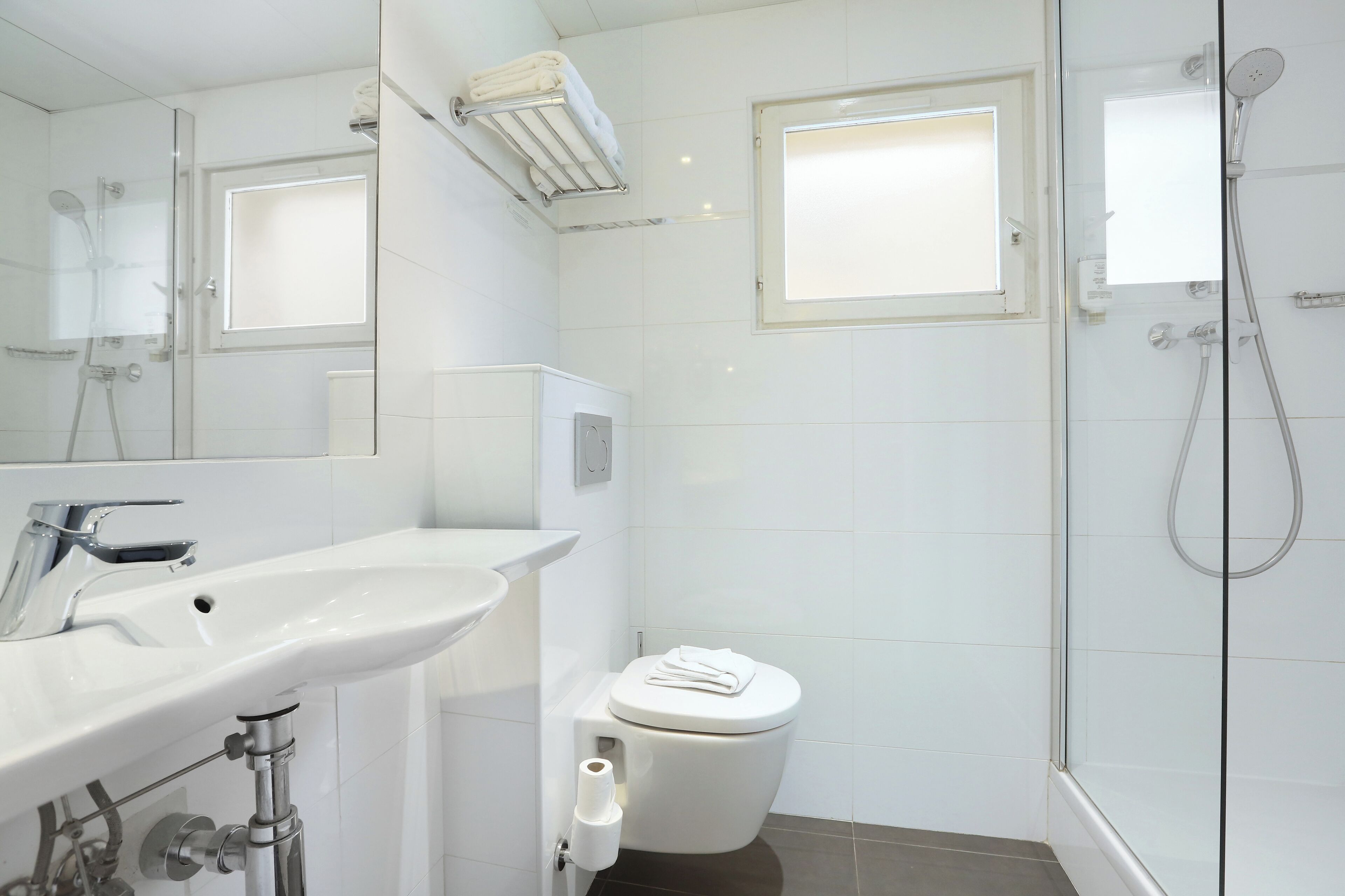 Une salle de bain moderne avec une douche à parois de verre, un lavabo blanc et des toilettes.