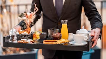 Uma bandeja com itens de café da manhã, incluindo croissants, muffins e um copo de suco de laranja.