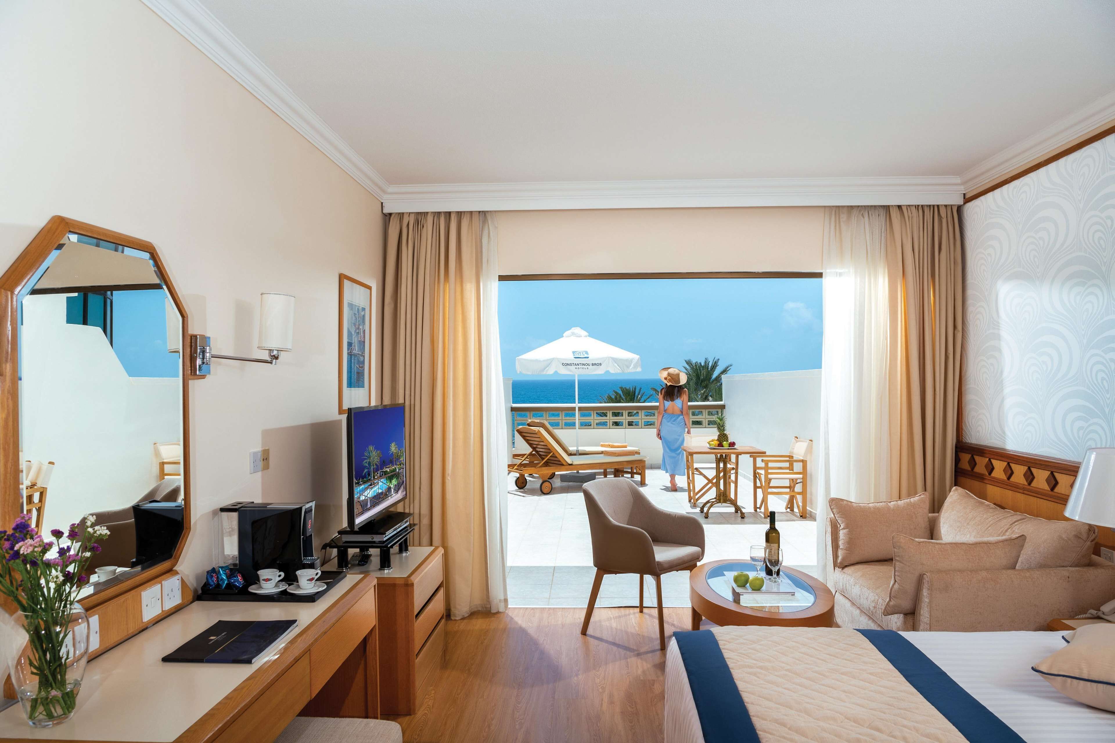 Habitación de hotel con cama, escritorio, televisor y vista al océano.