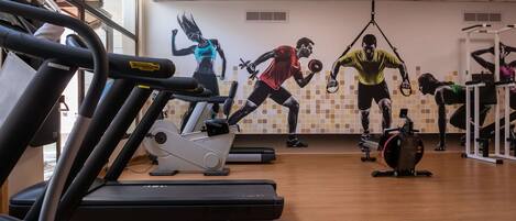 A gym with treadmills, a wall with fitness murals, and various exercise equipment.