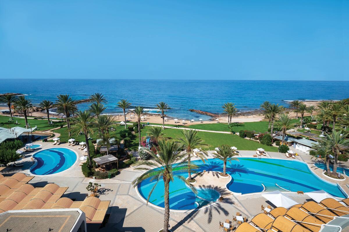 Un complexe hôtelier doté de plusieurs piscines, de palmiers et offrant une vue sur la plage.