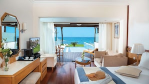 Une chambre d’hôtel avec un lit, un bureau, une chaise, une petite table et une vue sur l’océan.