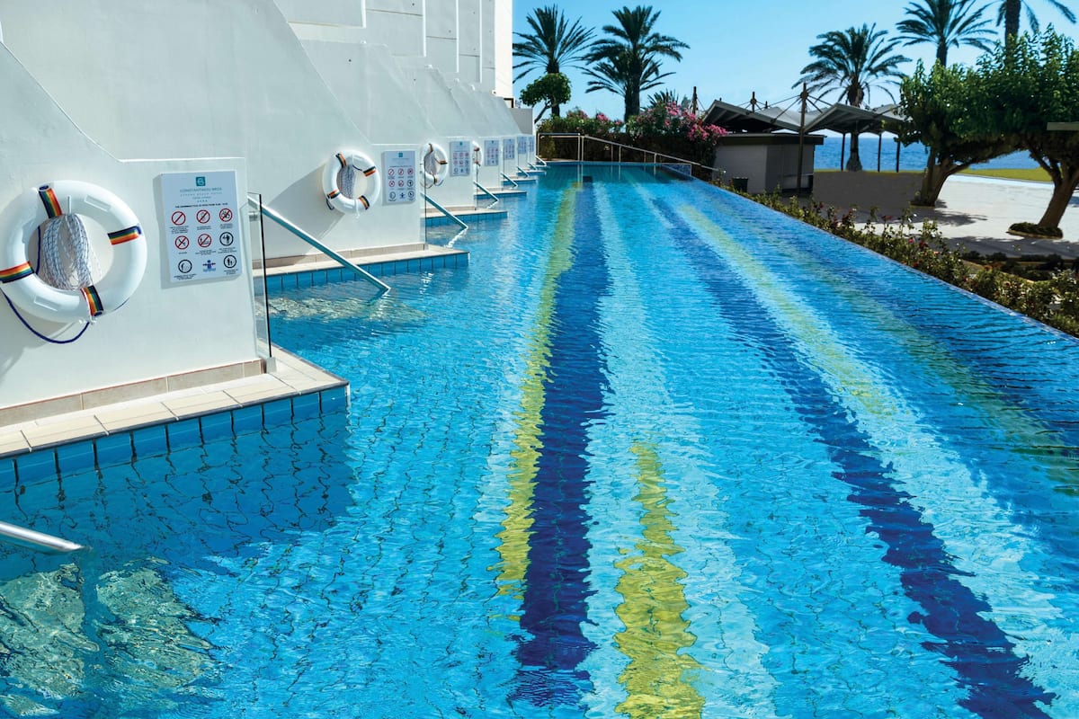 Une piscine avec une eau d’un bleu limpide, des bouées de sauvetage et un panneau indiquant les consignes de sécurité.