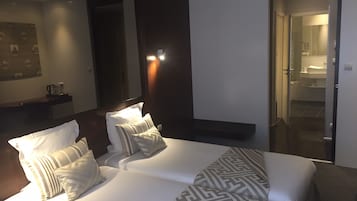 A hotel room with a large bed, a nightstand, a mirror, and a bathroom visible through an open door.