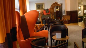 A hotel lobby with a large, ornate horse sculpture, leather armchairs, and a dining area. - Maison Lutetia R (Strasbourg)