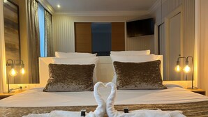 A hotel room with a large bed, two pillows, a flat-screen TV, and a bedside lamp. - Maison Lutetia R (Strasbourg)