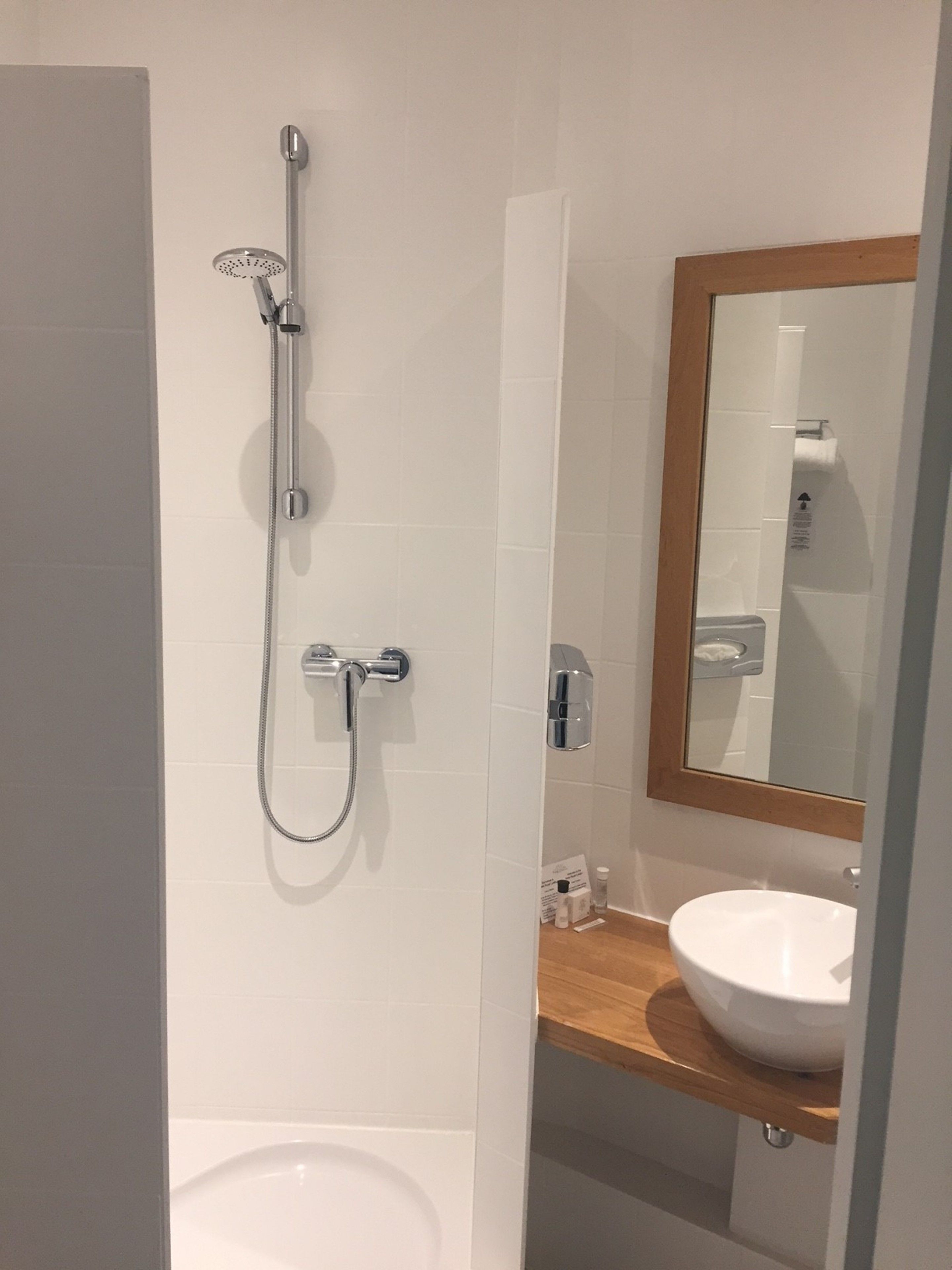 A bathroom with a shower, a sink, and a mirror.