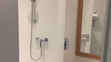 A bathroom with a shower, a sink, and a mirror.