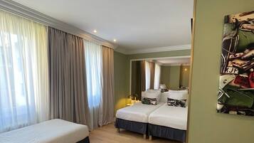 A hotel room with two single beds, a large mirror, and a green wall.