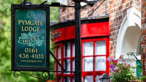 A sign for Pymgate Lodge Hotel with contact information and a website URL.